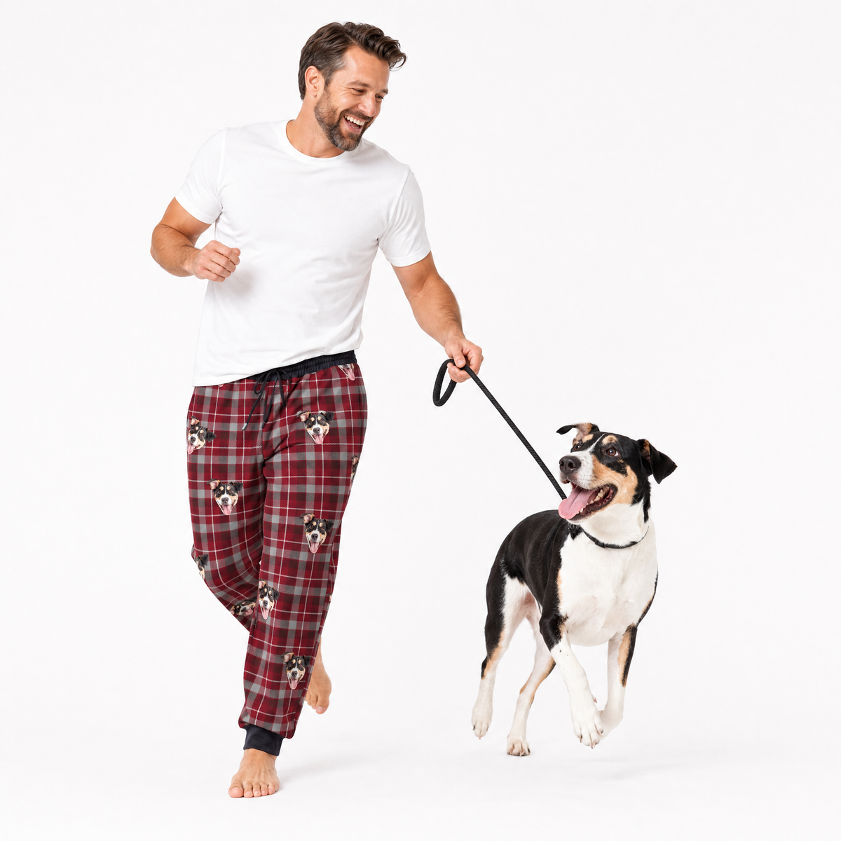 Man wearing plaid pajama pants with a dog on a leash against a white background