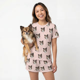 Woman wearing a pink pajama set with dog patterns, holding a small dog. [BlushBlossoms]