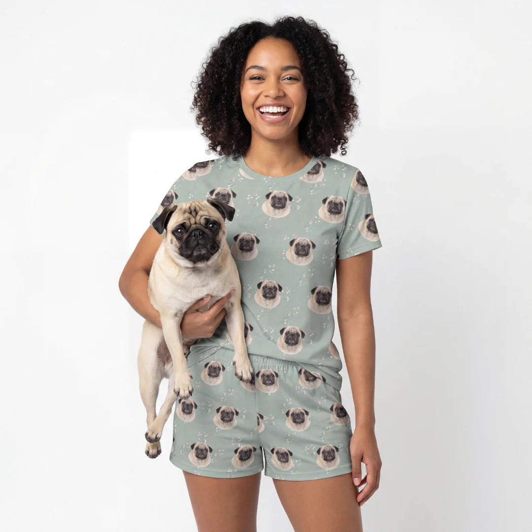 Woman wearing a pug-themed t-shirt and shorts pajama set, holding a pug dog. [VintageBloom]