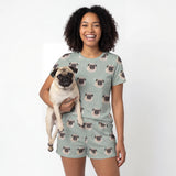 Woman wearing a pug-themed t-shirt and shorts set, holding a pug dog. [VintageBloom]