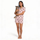 Woman wearing pink pajamas with dog print, holding a small dog, on a white background [BlushBlossoms