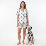 Woman wearing a patterned pajama set standing next to a Dalmatian dog on a white background [LilacStripes]