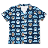 A short-sleeve collared button-up shirt with a repeating 'Free Ty Snowman' holiday print featuring cartoon dogs in snow globes, snowmen, and snowflakes on a dark navy background.