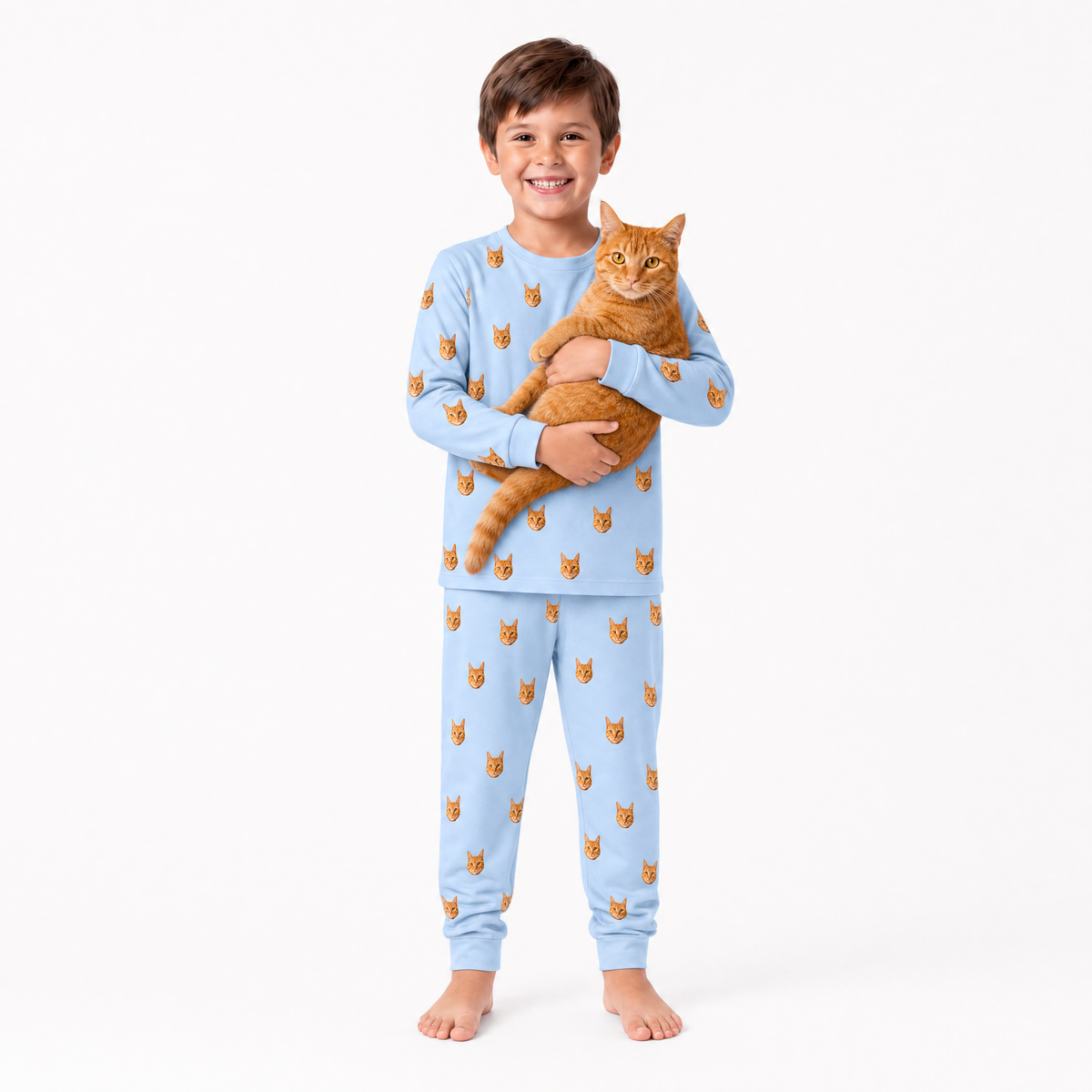 Child wearing sky blue jogger pajamas with cat pattern holding an orange cat on a white background