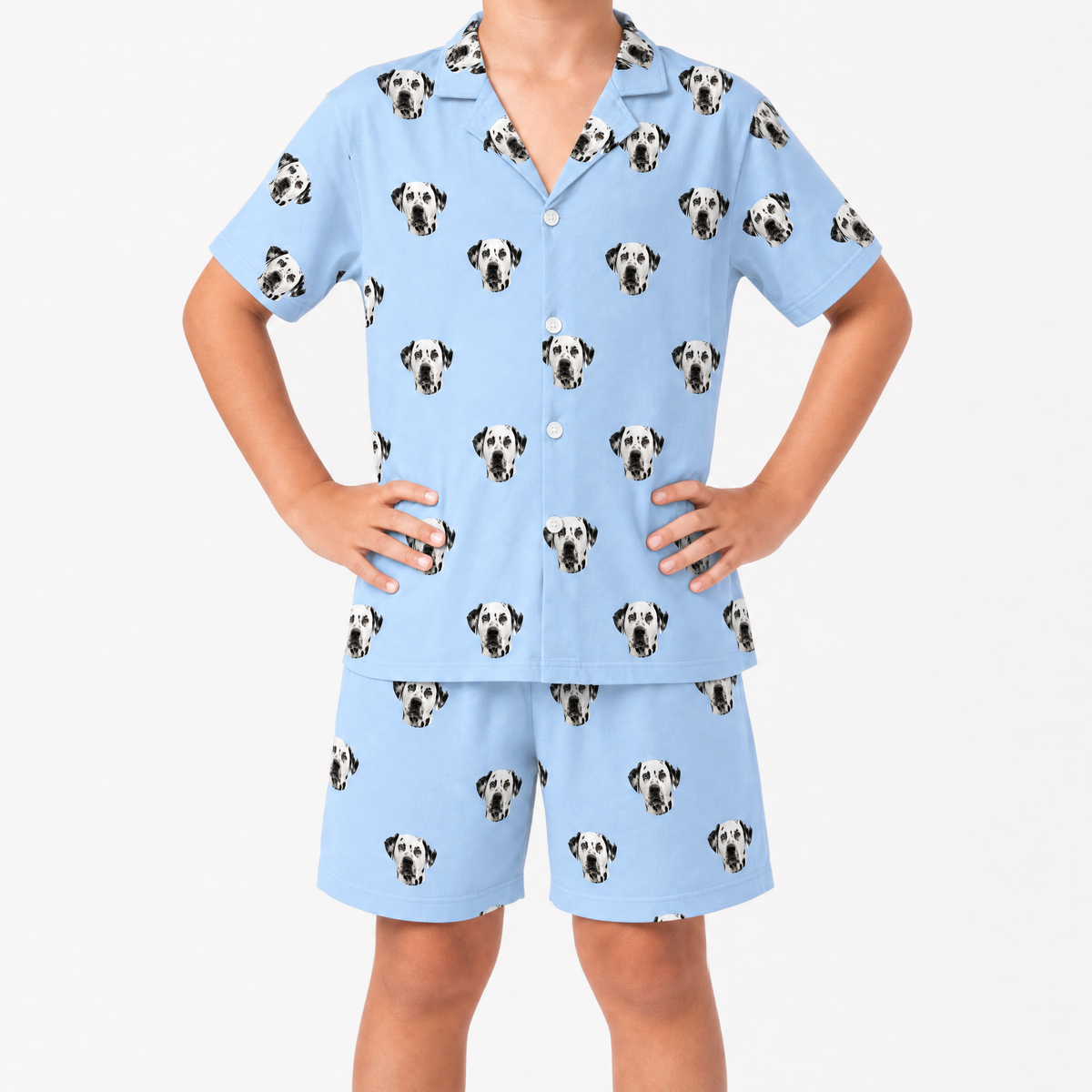 Child wearing a sky blue pajama set with dalmatian dog pattern on a white background