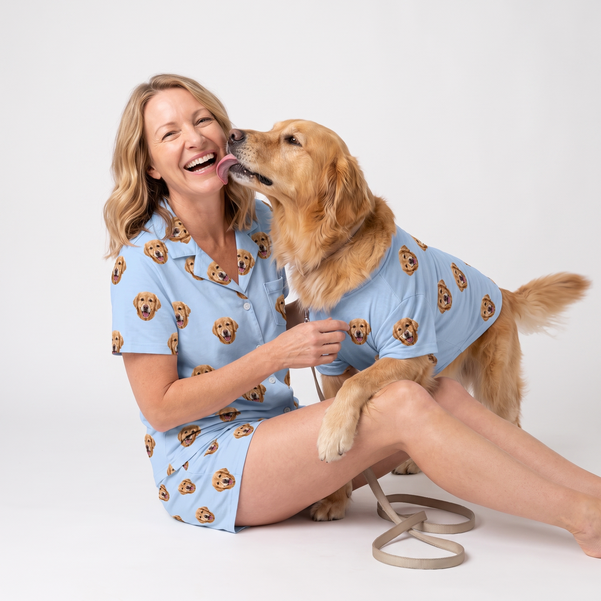 Woman and golden retriever wearing matching sky blue custom pet pajamas with a repeating dog face pattern.