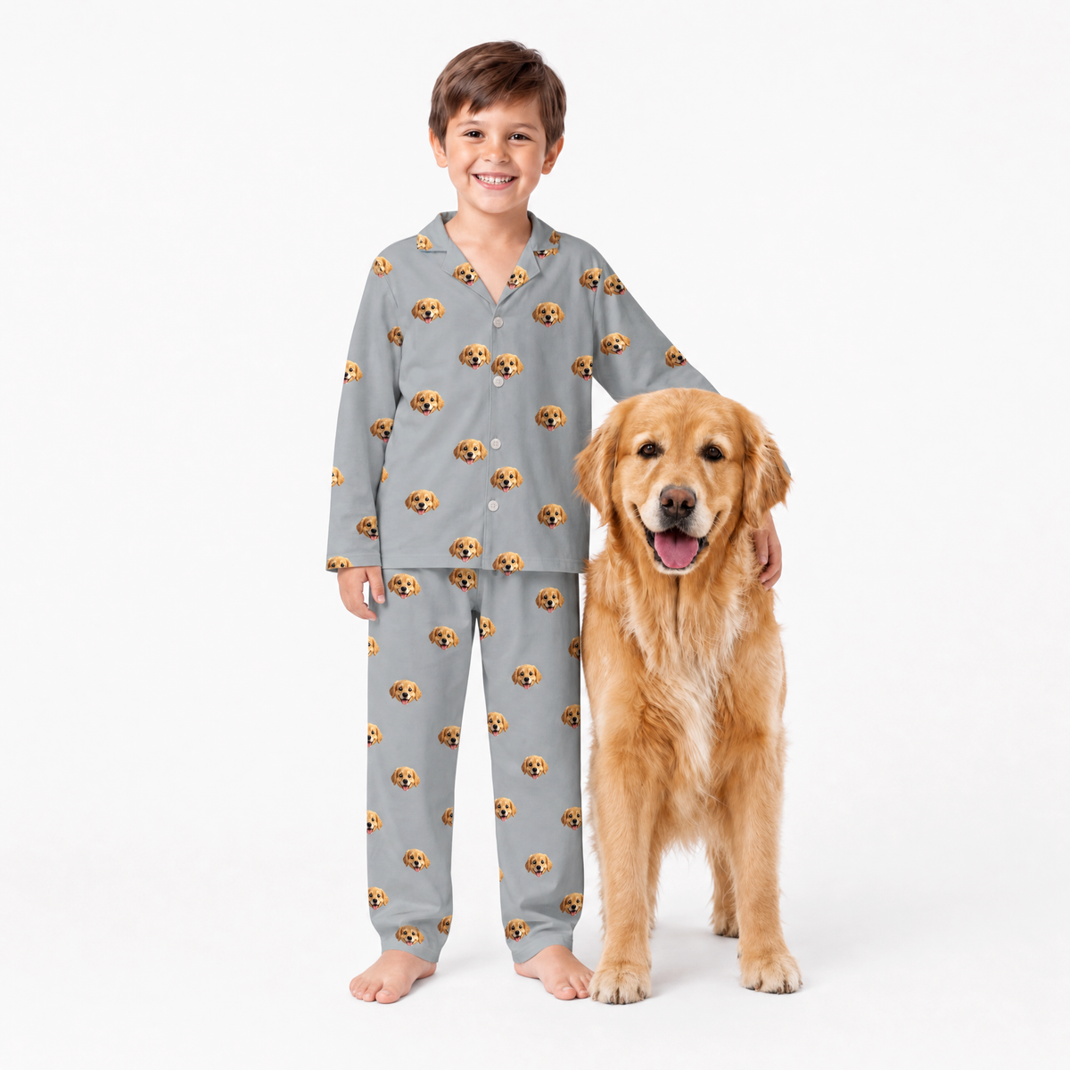 Child wearing gray pajamas with dog pattern standing next to a golden retriever on a white background