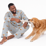 Man in pajamas playing with a dog on a white background