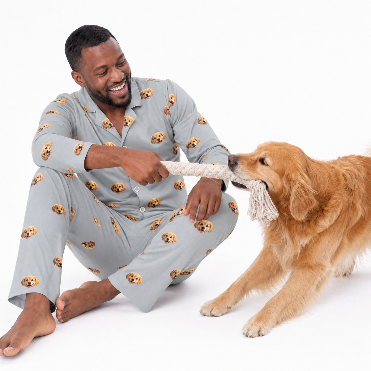 Man in pajamas playing with a dog on a white background