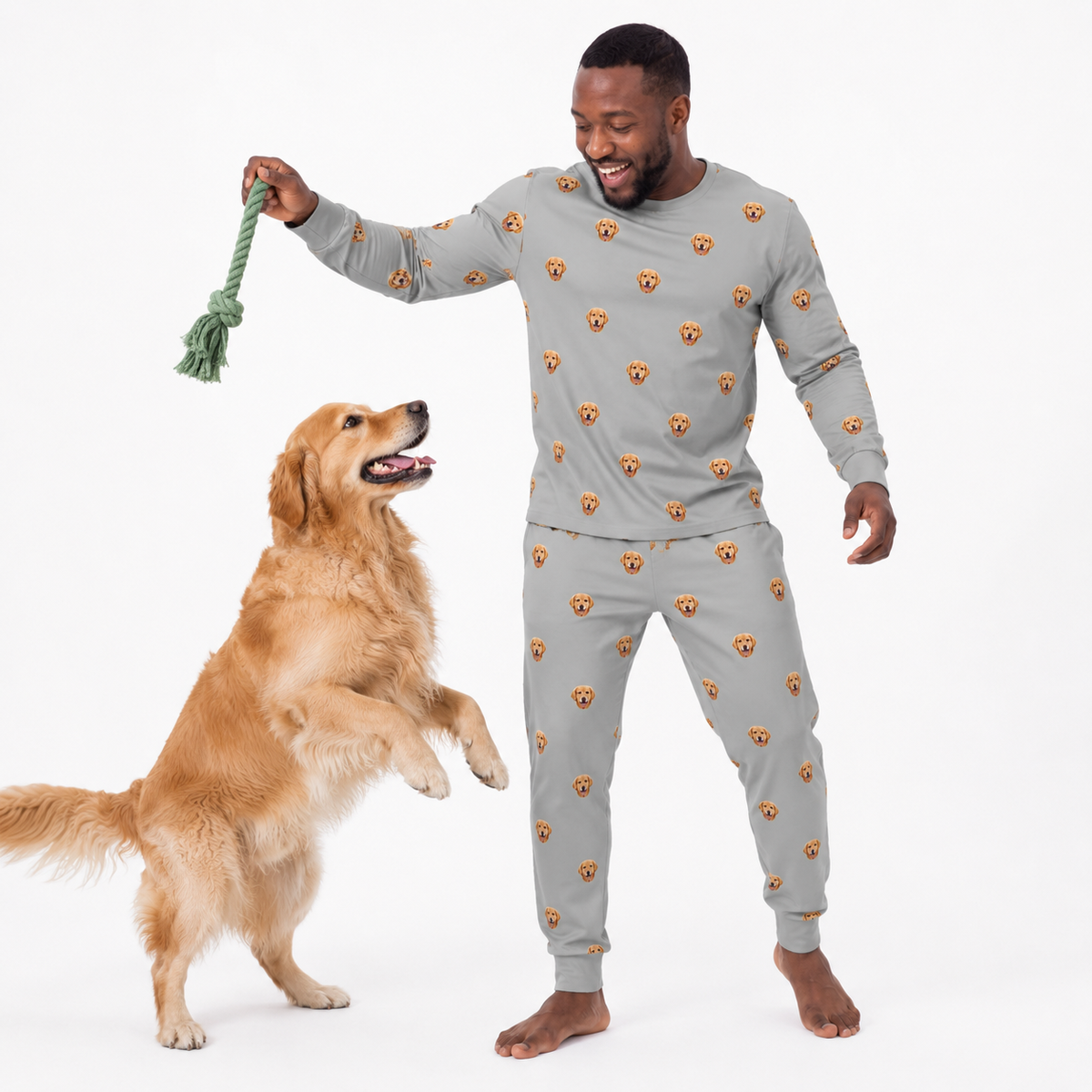 Man wearing a gray jogger pajama set with bear patterns standing next to a dog holding a green rope toy.
