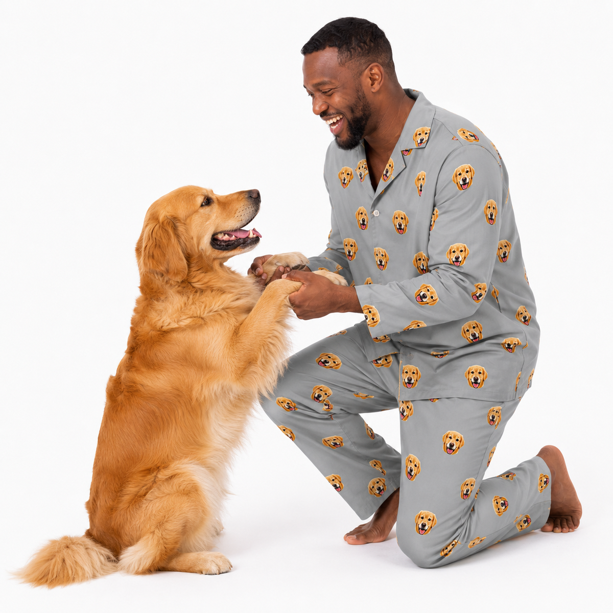 Man wearing gray pajamas with dog pattern interacting with a golden retriever on a white background