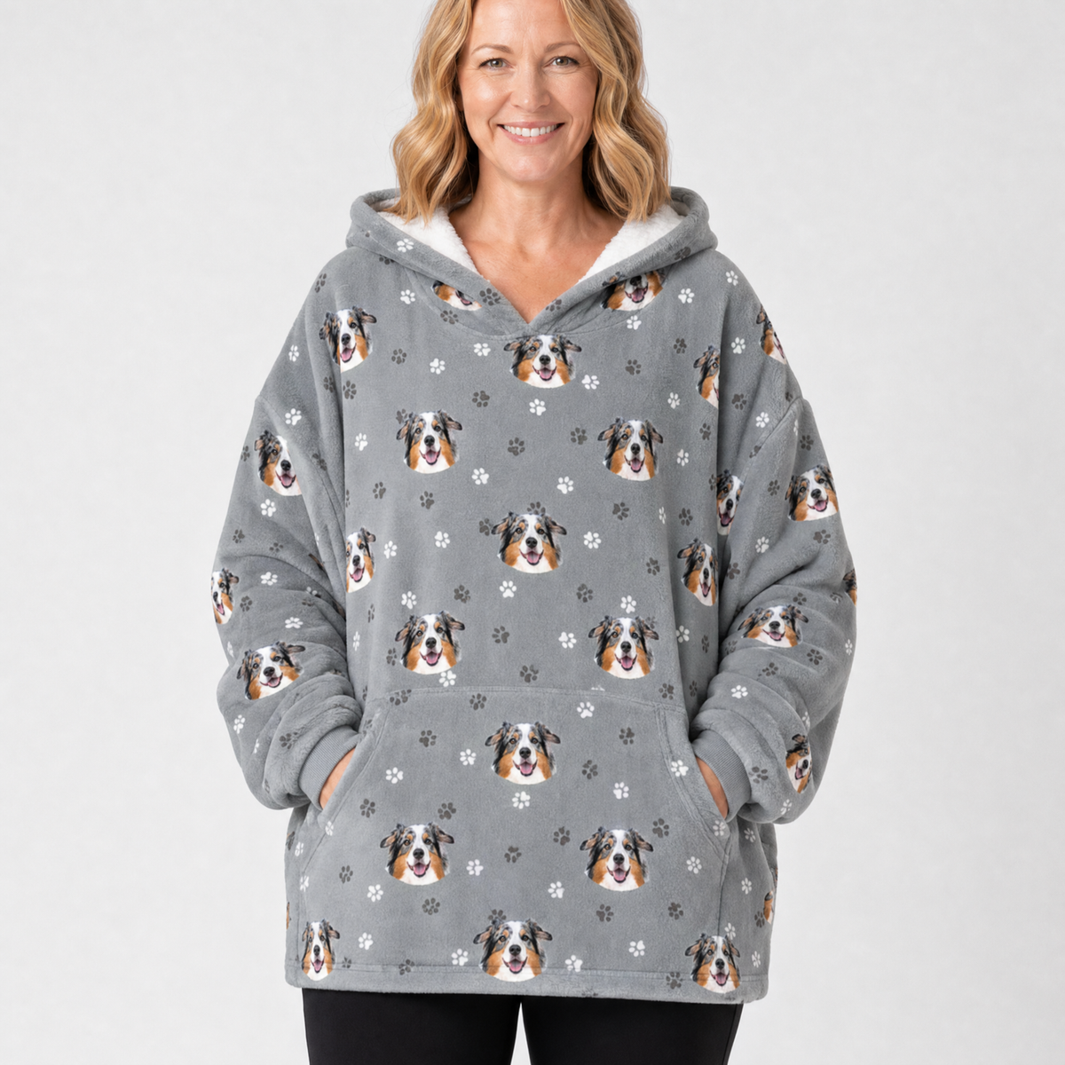Person wearing a gray blanket hoodie with dog pattern on a white background