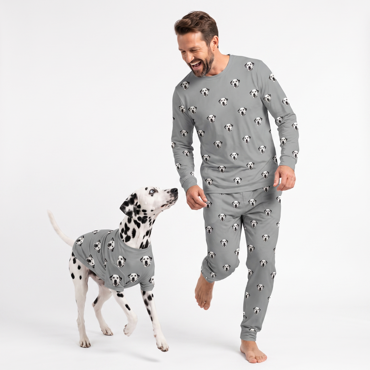 Man and Dalmatian wearing matching gray custom pet pajamas with a repeating dog face pattern.