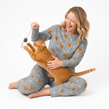 Woman wearing a Slate Gray cat-print pajama set sitting on the floor and playing with an orange cat using a dangling toy.