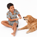 Child wearing a gray pajama set playing tug of war with a dog on a white background