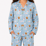 A model wearing a light blue long-sleeve pajama set with an all-over Christmas dog print, featuring golden retriever dogs, snowmen, and pine trees.