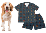 Dog next to a batman shirt and shorts set on a white background