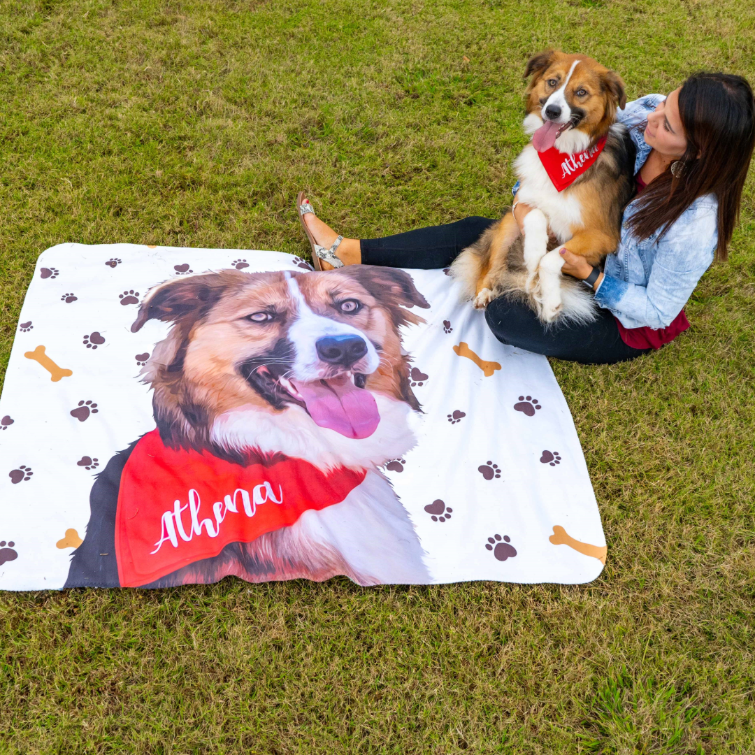 Woman on grass with dog and a white blanket featuring its illustrated portrait.