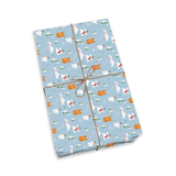 A rectangular gift box wrapped in light blue wrapping paper with a repeating pattern of white dogs, orange foxes, and small green trees, tied with a brown twine bow. The box is photographed on a clean white background.