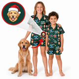 A matching children's pajama set shown on two models, a girl and a boy, alongside a golden retriever. The pajamas are dark green with a cartoon dog print and a Santa hat motif.