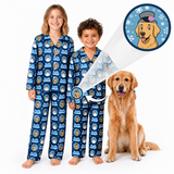 Two children wearing matching blue patterned pajamas stand barefoot on a white background next to a golden retriever dog. A circular inset shows a cartoon golden retriever wearing a hat, with arrows pointing to the child's pajama print and the dog's collar area, suggesting the pajamas are printed or designed for pets.