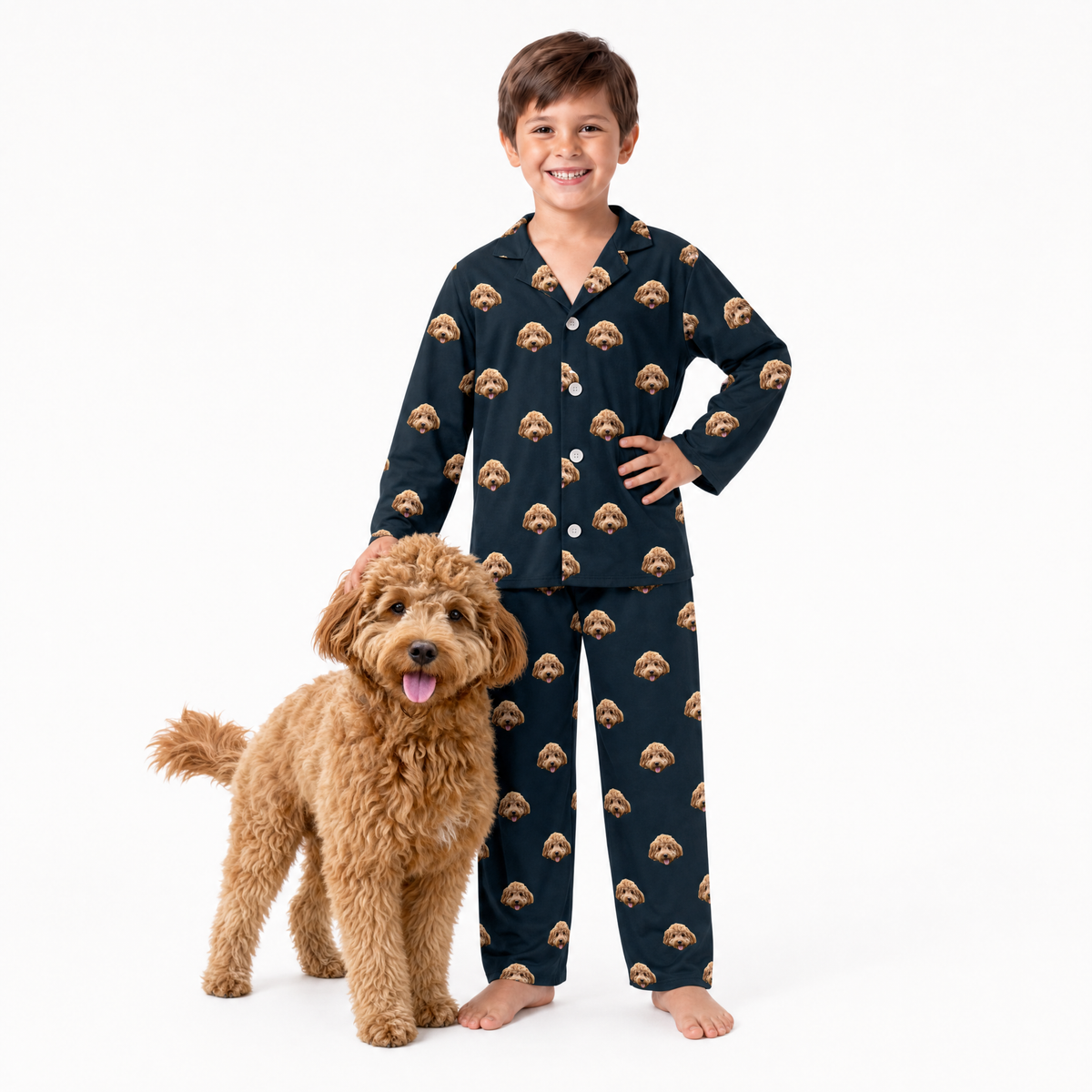 Child wearing black pajamas with dog pattern standing next to a brown dog on a white background