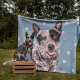 Black & gray dog on a wood crate by a blue paw print blanket with its custom portrait.