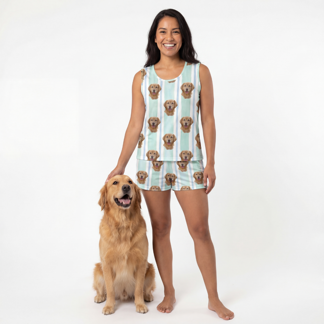 Woman wearing tank top pajamas with dog pattern, standing next to a dog on a white background