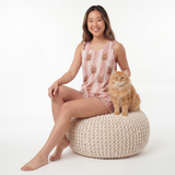 Woman wearing tank top pajamas set with a cat beside her on a white background